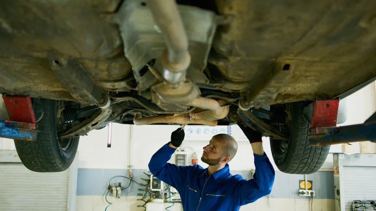 Mechanik przy podwoziu samochodu na podnośniku