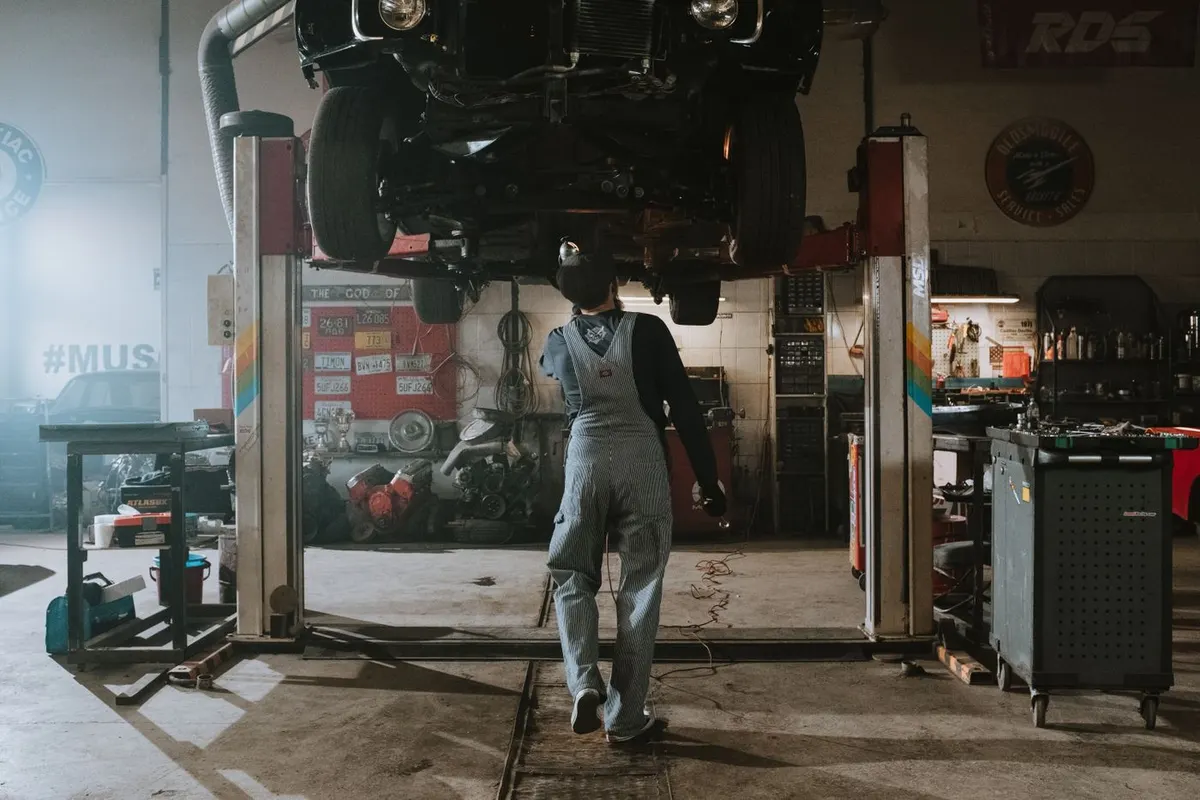Mechanik pracuje przy samochodzie uniesionym na podnośniku