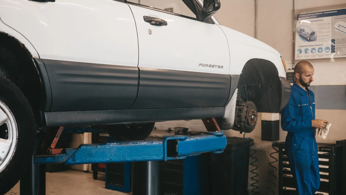 Dwóch mechaników pracujących przy samochodach w warsztacie