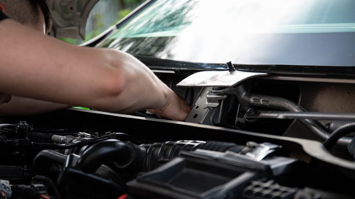 Mechanik pracuje nad silnikiem samochodu, koncentrując się na naprawie przekładni bezstopniowej