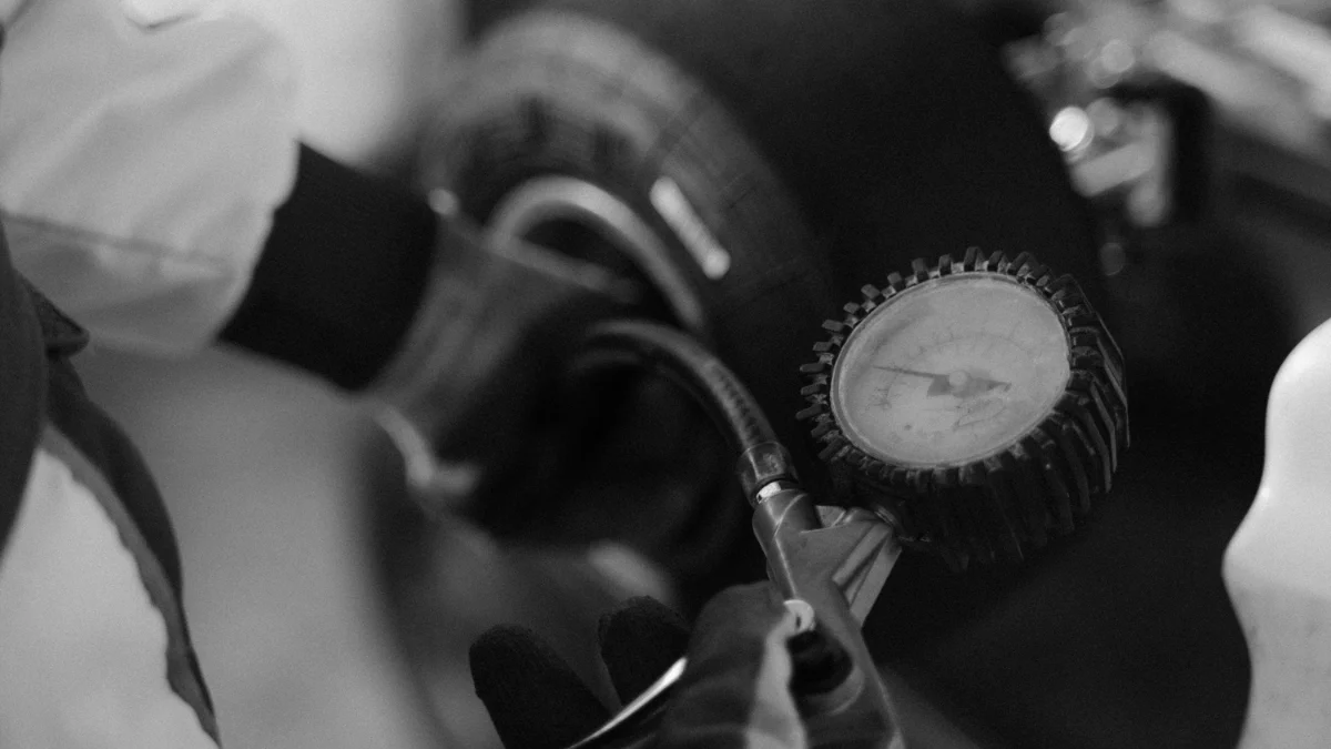 Mechanik w trakcie pomiaru ciśnienia w oponie na kole kartingu, wykorzystując manometr, w stanie pracy