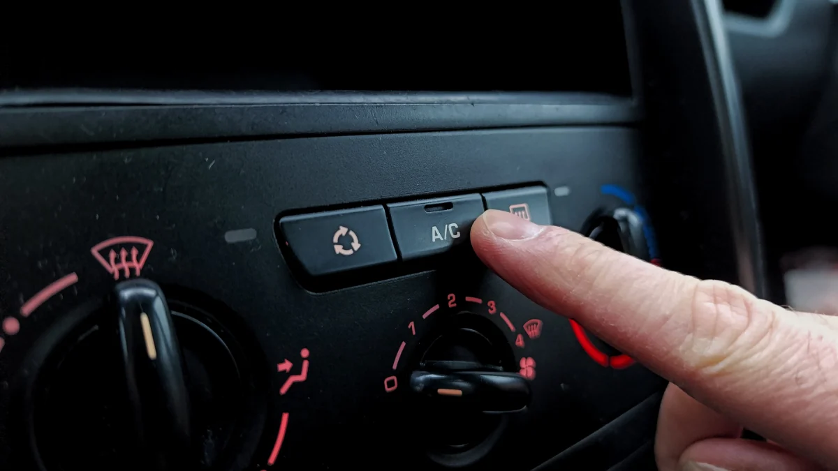 Mechanik serwisujący układ klimatyzacji samochodowej za pomocą stacji warsztatowej