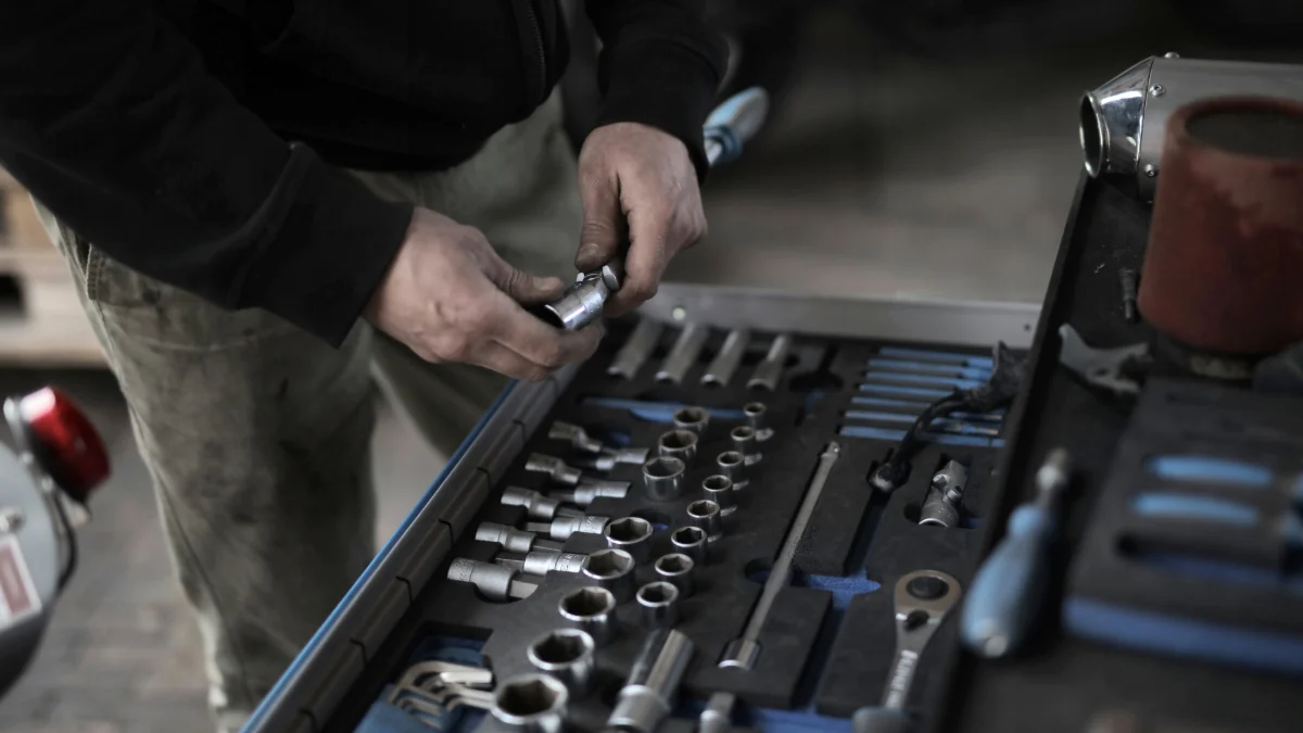 Osoba po studiach ucząca się praktycznej mechaniki samochodowej w warsztacie