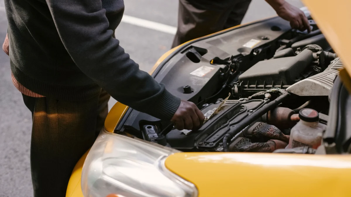 Dwóch mechaników badających i naprawiających silnik żółtej taksówki na drodze, co może być związane z problemami z żywotnością danych