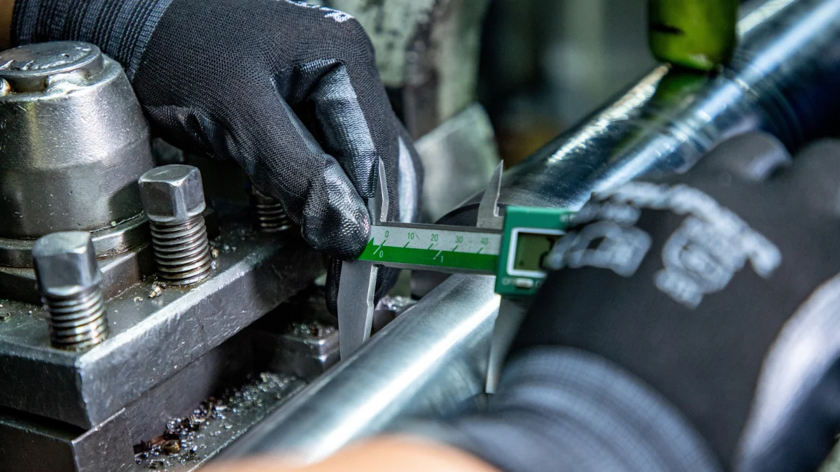 Mechanik wykonujący pomiar mikrometrem i czujnikiem zegarowym w warsztacie
