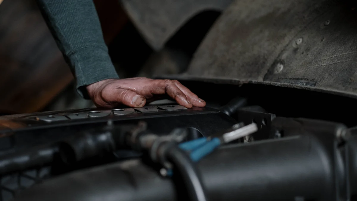 Mechanik sprawdza silnik samochodu, pokazując precyzję i ekspertyzę w utrzymaniu pojazdów, w tym w warunkach sieci fast fit
