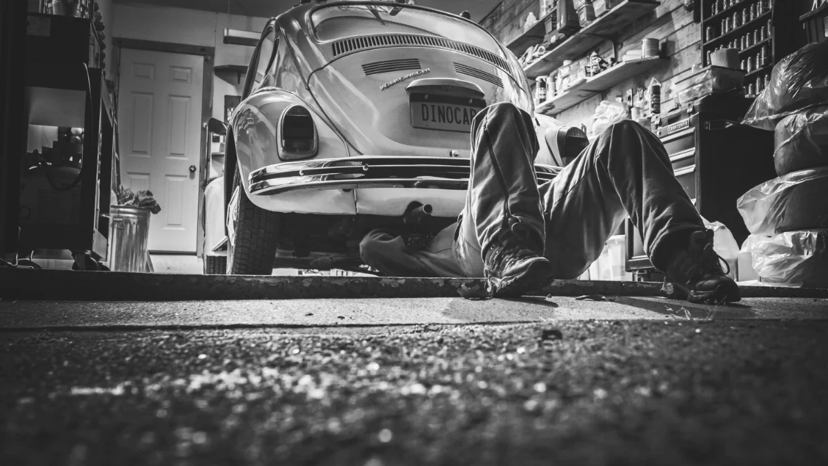 Mechanik pracuje w vintage garażu pod klasycznym Volkswagenem Beetle, symbolizując tradycyjne warsztaty mechaniczne