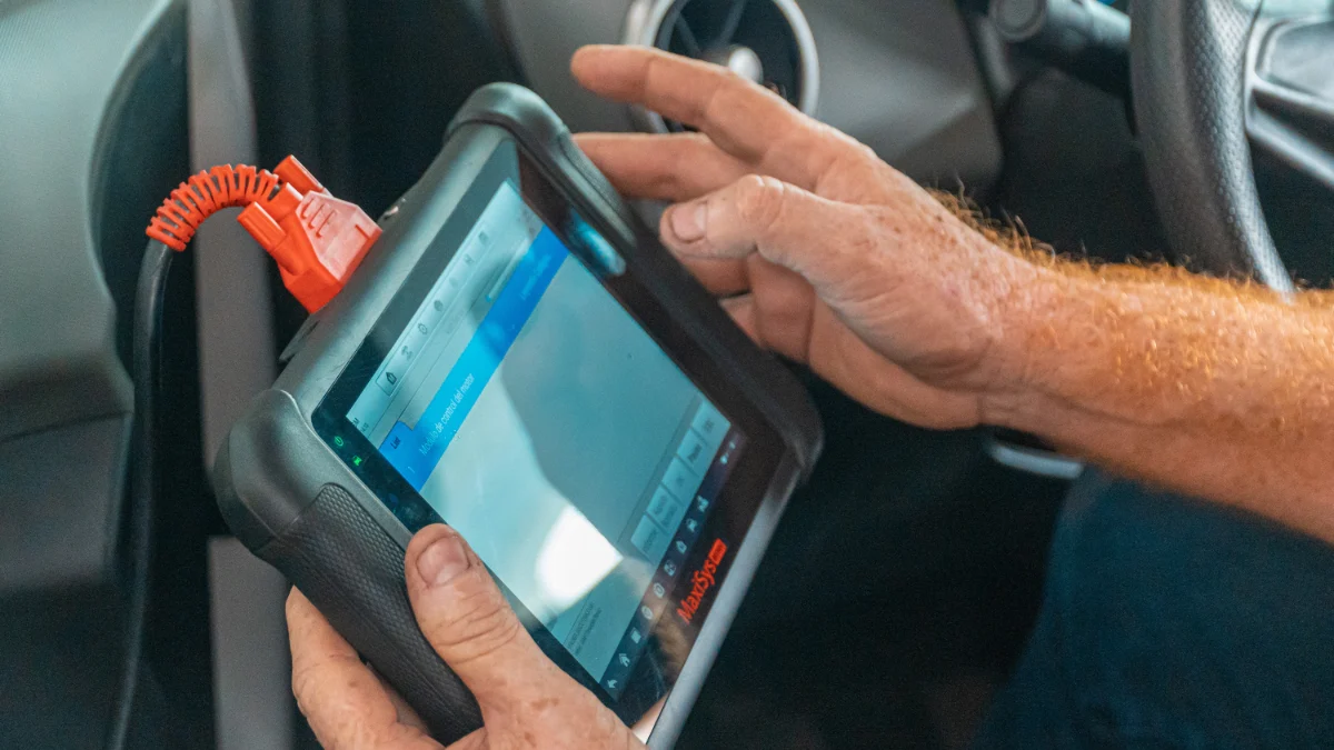 Mechanik korzystający z testera diagnostycznego przy samochodzie
