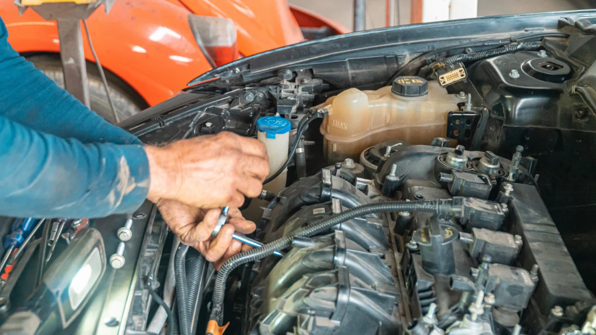 Mechanik naprawia silnik samochodowy w garażu, wykazując swoją techniczną precyzję podczas pracy